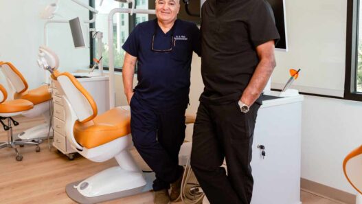Two dental practitioners in scrubs standing inside a modern treatment room at the Austin Institute of Dental Medicine.